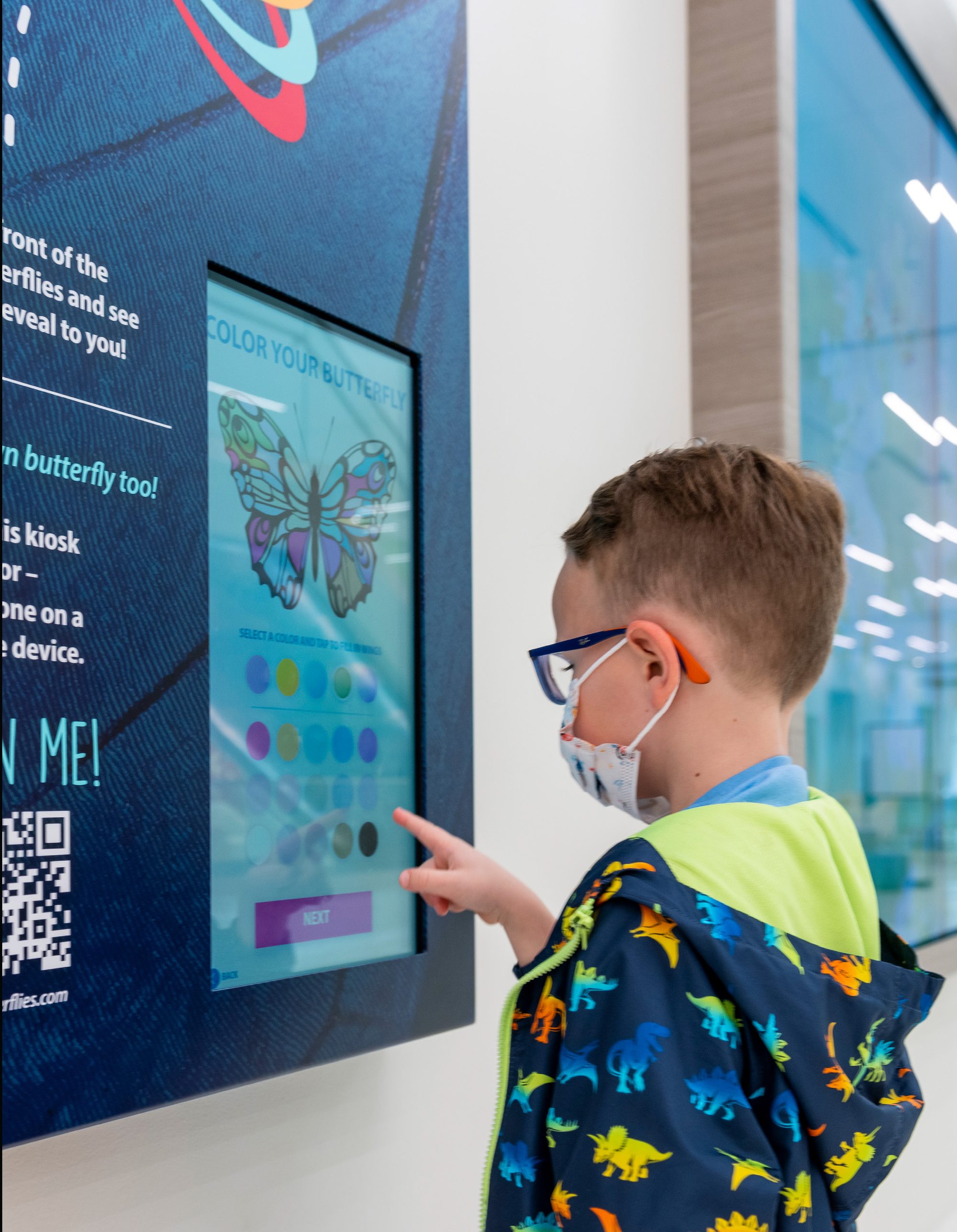 Child designing a butterfly at the touchscreen kiosk